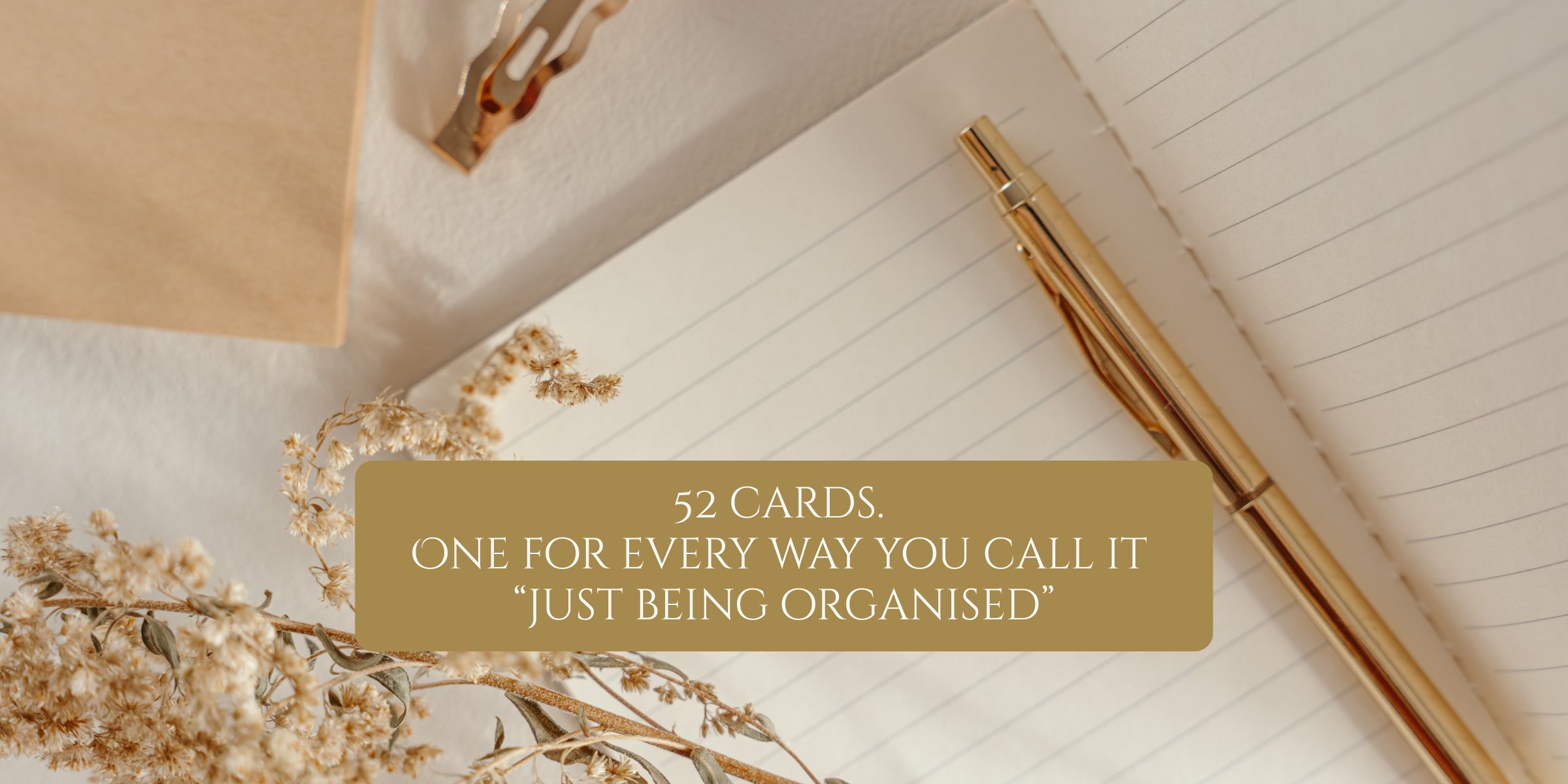 52 cards. One for every way you call it &ldquo;just being organised.&rdquo; A gold pen, cream notebook, and dried flowers laid out on a warm tan surface.